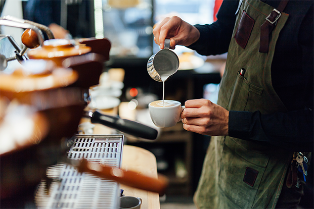 coffee shop worker pouring milk